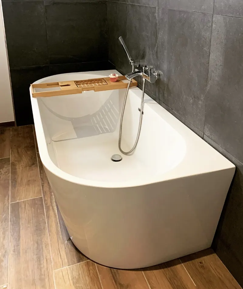 Baignoire en îlot blanche, robinetterie fixée au mur gris