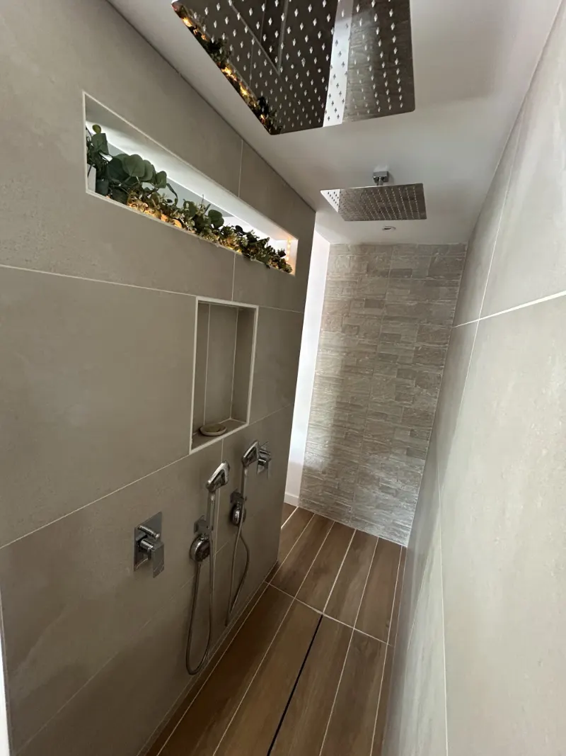 Douche à l'italienne avec pommeau de pluie, niche dans le mur et jardinière éclairée au-dessus de la cloison