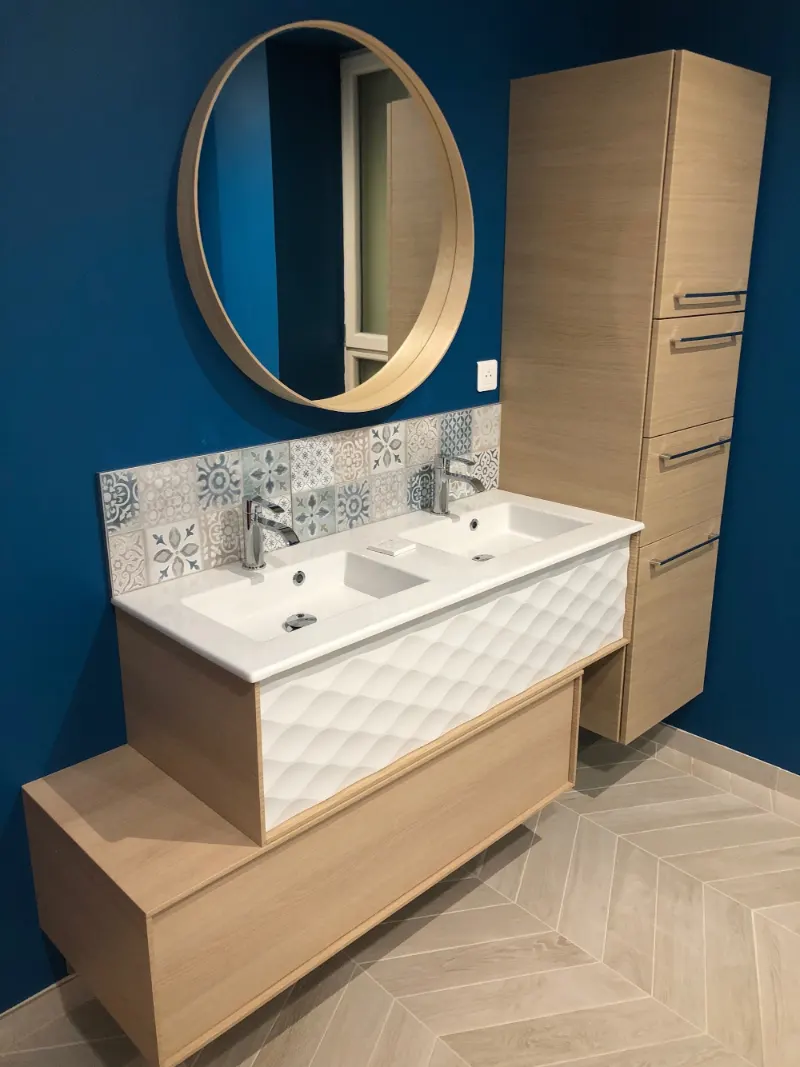 Double vasque sur un meuble en bois, mur bleu et miroir rond