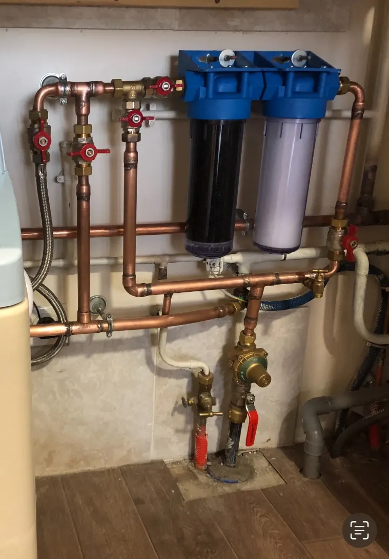 Une installation de plomberie en cuivre, avec ses vannes et deux filtres à eau