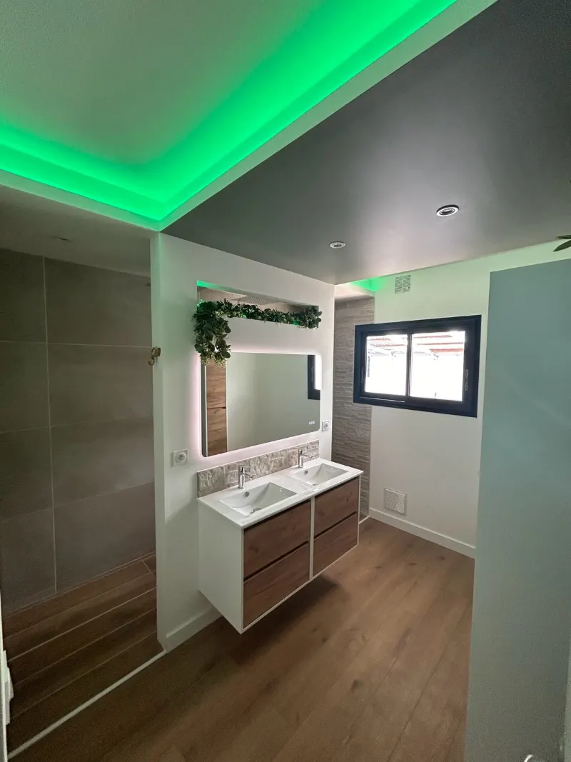 Salle de bain avec plafond lumineux, double vasque et miroir éclairé